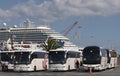 Cruise ship passenger buses wait for passengers in port.