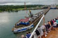 A cruise ship with the passengers on the bow watching the ship being tied to the mule train locomotives