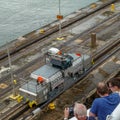 A cruise ship with the passengers on the bow watching the ship being drug by a mule train locomotives at the Panama Canal