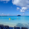 Cruise Ship passengers enjoying a day at the beach on the private island with a cruise ship anchored in the background