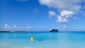 Cruise Ship passengers enjoying a day at the beach on the private island with a cruise ship anchored in the background