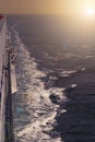 Cruise ship sailing at sea with wake waves and hand rails in the sunset Royalty Free Stock Photo