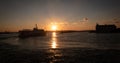 A cruise ship at sunset and the city skyline far behind, orange sky, silhouette. Royalty Free Stock Photo