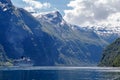 Cruise vessel inside the fjord leaving Geiranger with big mountains peak in the background