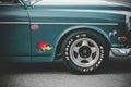 A closeup shot of the side of a green vintage car with stickers above the wheel