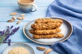 Crumble cookies with seasme and almonds on ceramic plate with cup of coffee on blue wooden background. side view, close up