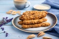 Crumble cookies with seasme and almonds on ceramic plate with cup of coffee on blue wooden background. side view, close up,