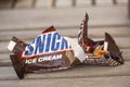 Crumbled and torn paper from a Snickers Ice Cream bar thrown on wooden floor. Close up