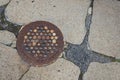 Crumbling concrete and asphalt sidewalk with old glass and cast iron manhole cover