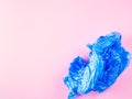 Crumpled blue plastic trash bag on pink background