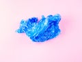 Crumpled blue plastic trash bag on pink background