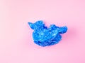 Crumpled blue plastic trash bag on pink background