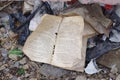 Crumpled dirty torn book lies on the ground among various rubbish