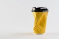 Yellow crumpled disposable paper coffee cup, out of shape, trash, recycle