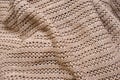 Crumpled folded beige, brown knitted fabric background, woolen knitwear plaid close up