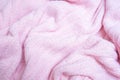 Crumpled folded light pink soft cozy knitted fabric background, washing woolen knitwear and delicate textile concept