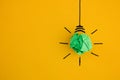 Crumpled green paper light bulb on yellow background Royalty Free Stock Photo