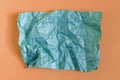 Crumpled green paper on an orange background. The texture of the crumpled paper