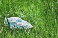 Crumpled medical protective mask lies on the grass