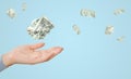 Crumpled one dollar bills flying over female hand on blue background Royalty Free Stock Photo