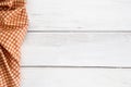 Crumpled orange checkered tablecloth or napkin on empty white wooden table with copy space for food cooking menu background