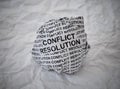Crumpled paper ball with words Conflict Resolution on crumpled white paper background Royalty Free Stock Photo