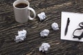 Crumpled paper balls with eye glasses mug, pen and notebook Royalty Free Stock Photo