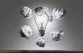 Crumpled paper balls flying arround light bulb