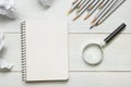 Crumpled paper balls, magnifying glass, pencils and notebook with blank white sheet on wooden table. Creativity crisis Royalty Free Stock Photo