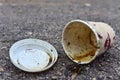 Crumpled a paper coffee cup on asphalt. Discarded disposable coffee cup with a plastic lid on road. Out of shape crushed paper cup