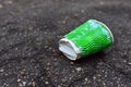 Crumpled a paper coffee cup on asphalt. Discarded disposable coffee cup with a plastic lid on road. Out of shape crushed paper cup