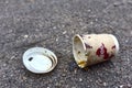 Crumpled a paper coffee cup on asphalt. Discarded disposable coffee cup with a plastic lid on road. Out of shape crushed paper cup