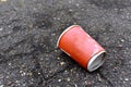 Crumpled a paper coffee cup on asphalt. Discarded disposable coffee cup with a plastic lid on road. Out of shape crushed paper cup