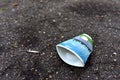 Crumpled a paper coffee cup on asphalt. Discarded disposable coffee cup with a plastic lid on road. Out of shape crushed paper cup