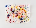 Crumpled paper splattered with vibrant multicolor paint on white background. Minimal abstract colorful idea. Flat lay