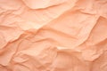 Crumpled peach fuzz color paper texture background. The wrinkled design paper, fabric folds, crumpled fabric. Close up