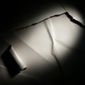 Crumpled paper with torn edges is illuminated in partial darkness, creating a dramatic Royalty Free Stock Photo