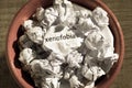 Crumpled paper written xenofobia, portuguese and spanish word for xenophobia, inside the trash can. Paper balls. Concept of old