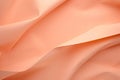 Crumpled peach fuzz color paper fabric texture background, fabric folds