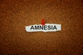 A crumpled piece of paper with the word Amnesia on it pinned to a corkboard