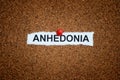 A crumpled piece of paper with the word Anhedonia on it pinned to a corkboard Royalty Free Stock Photo