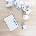 crumpled sheets of paper next to a notepad and a ballpoint pen on a wooden table. Royalty Free Stock Photo
