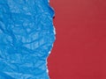 Crumpled and torn blue paper on a background of plain red paper Royalty Free Stock Photo