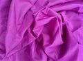 crumpled and wavy surface texture of bright pink cotton cloth.