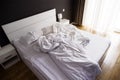 Crumpled white bed with set of white bed linen in bedroom in the early morning