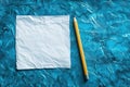Crumpled White Paper and Yellow Pencil on a Blue Textured Surface Royalty Free Stock Photo
