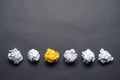 Crumpled yellow paper ball among white balls