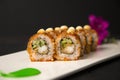 Crunchy Japanese sushi roll with tempura shrimp, flowers, painting brush strokes on white plate, Wooden background Royalty Free Stock Photo