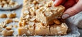 Crunchy peanut brittle being broken, showcasing texture and peanuts on white background