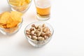 Crunchy snacks for beer. Nachos, pistachios and chips in glass plates and light ale in glass